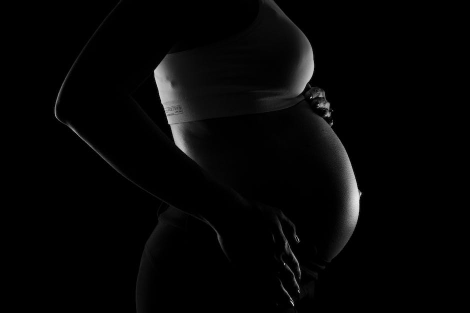 A serene image of a pregnant woman resting with her eyes closed and hands on her abdomen, promoting rest and relaxation during pregnancy.